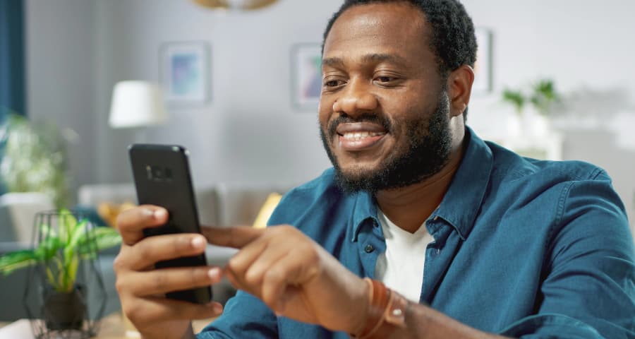 Man sitting down interacting with a home security app on his smartphone